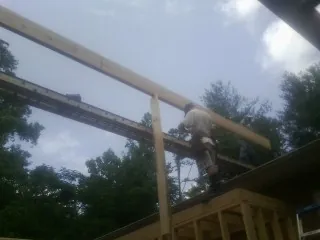 Carpenter setting a ridge beam over a new addition frame — Ice Dam Removal by Roofing Brothers in Ellisburg