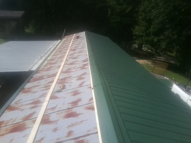 Old rusted panels beside newly installed green metal roofing — Wind Damage Roof Repair by Roofing Brothers in Ellisburg