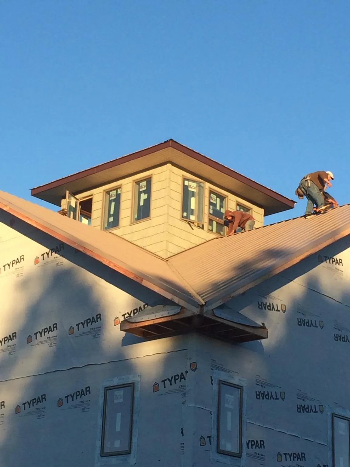 Roofers working around a rooftop cupola on a new metal roof at sunset — Roof Waterproofing in Ellisburg by Roofing Brothers